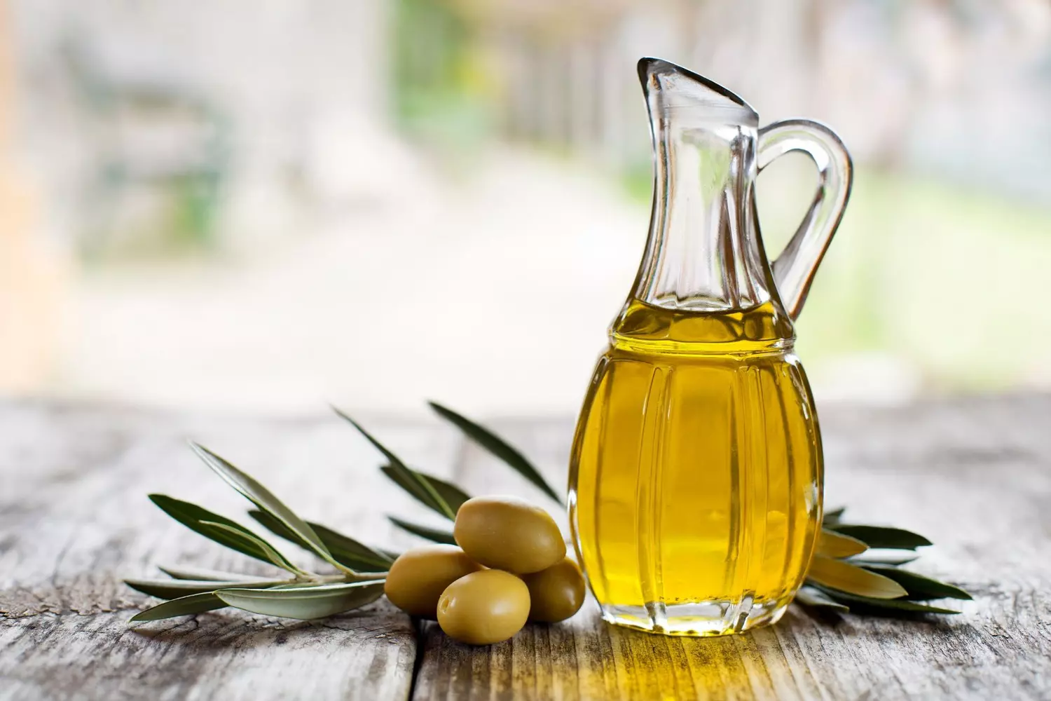Carafe d'huile d'olive et olives fraîches sur une table en bois